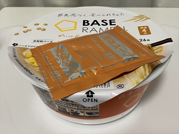 ベースラーメンのカップにお湯を入れ、待っている状態の画像。液体スープを上に乗せてあたためている。